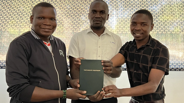 Kwamshi Bible Translators holding the new testament bible